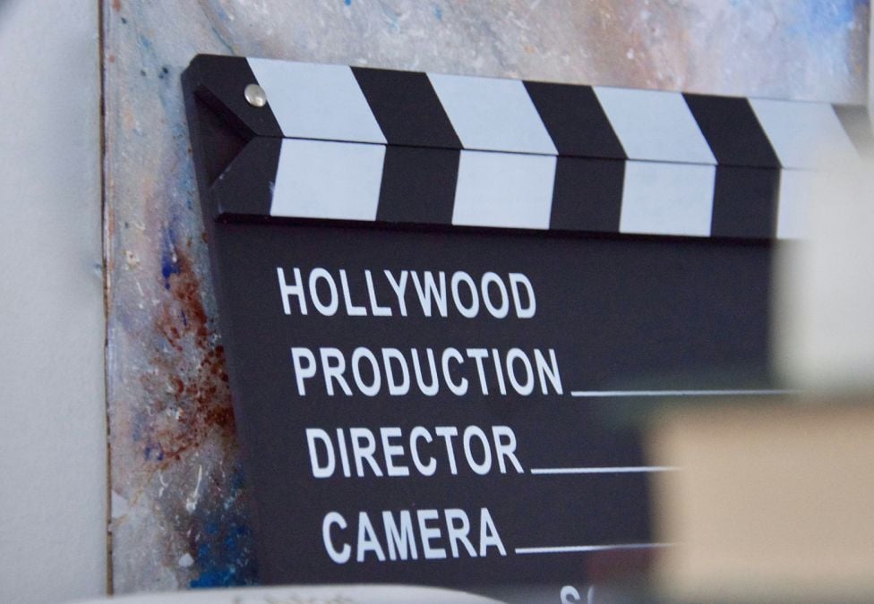 An up close image of a clapperboard which has the words "Hollywood", "Production", "Director", and "Camera". The image is a header image leading to an article from the Milken Institute about the challenges in funding streams and financing facing the entertainment industry.