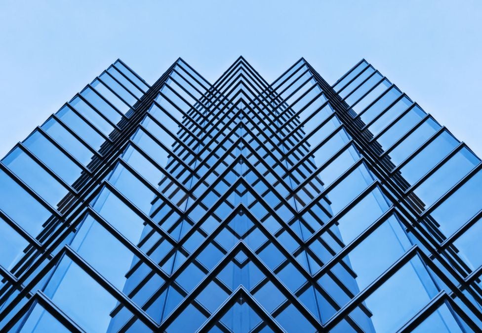 Upward view of a tall glass building with symmetrical repeating window patterns.