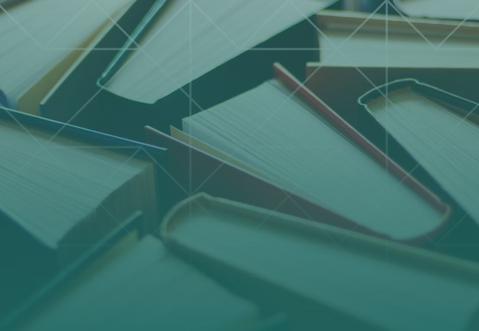 Overhead view of open and closed books layered together, creating a textured pattern that represents knowledge and learning.