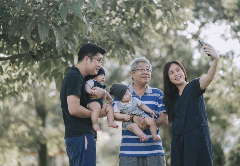 Family taking a selfie together in a sunny park.
