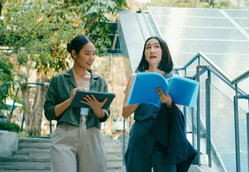 Two colleagues review documents in front of solar panels, highlighting collaboration in clean energy innovation.