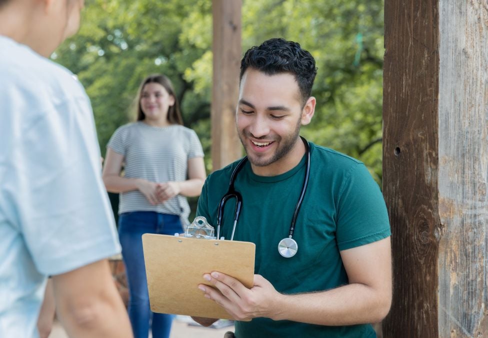 Delivery person in green shirt handing package to customer at doorstep