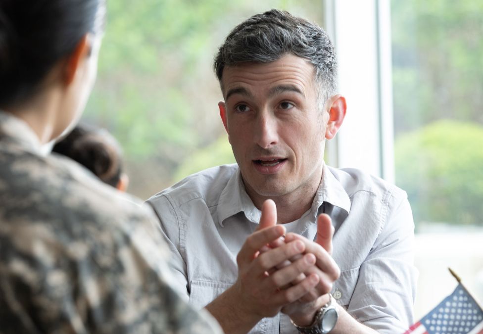Businessman in white shirt listening attentively with clasped hands during meeting