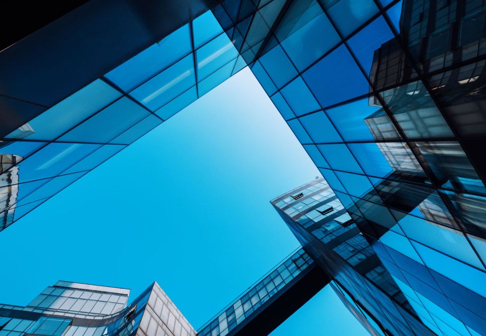 Upward view of modern glass skyscrapers reflecting a clear blue sky.