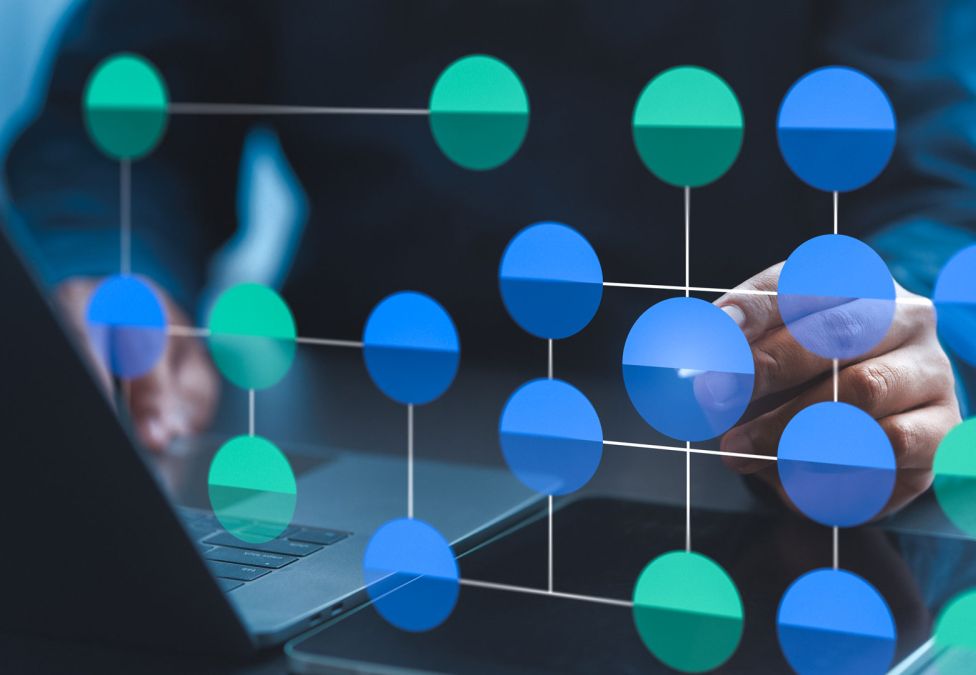 A person working on a laptop with a digital overlay of a connected network of blue and green nodes, representing data or blockchain technology.