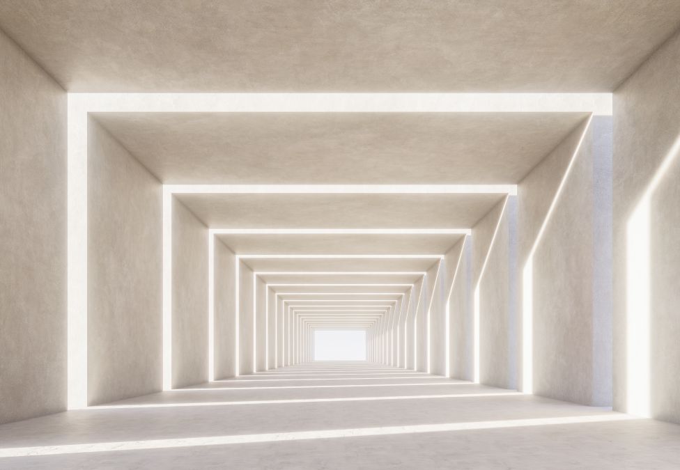 A long minimalist corridor with repeating rectangular archways in warm white concrete, receding toward a bright vanishing point.
