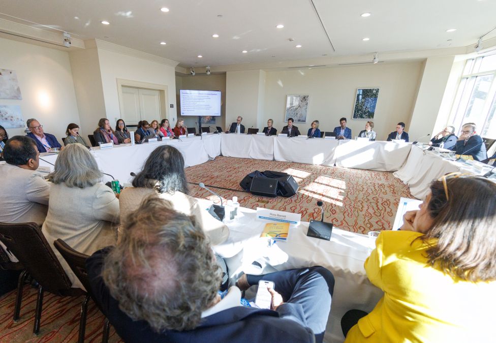 Business meeting with diverse group seated around U-shaped table configuration in conference room