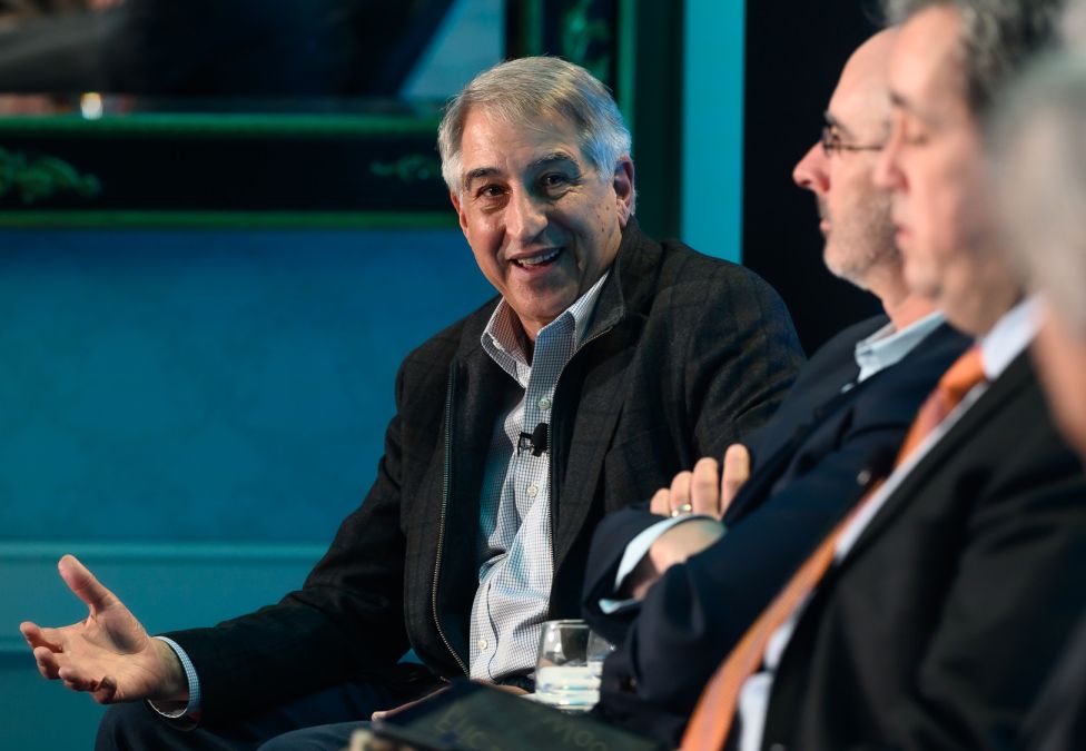 Two men in business attire engaged in discussion during a panel or meeting