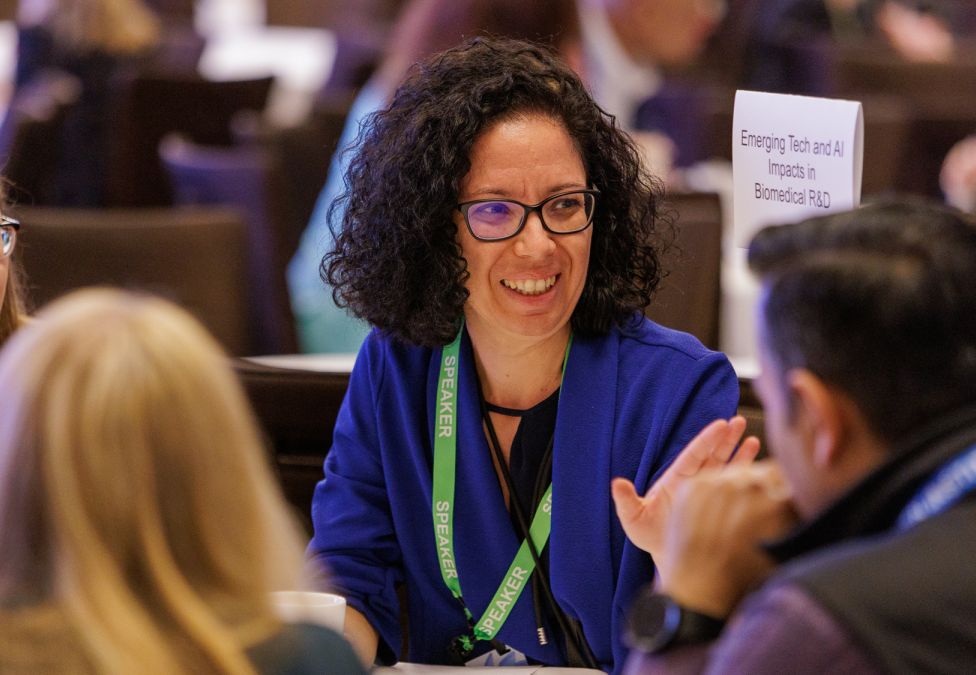 Professional woman in glasses and blue cardigan engaged in conversation at business conference