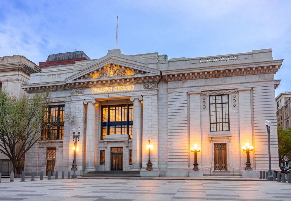 Milken Center in Washington, DC, a classical white stone building with illuminated columns at dusk