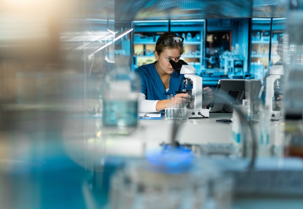 Scientist at a computer in laboratory with blue lighting