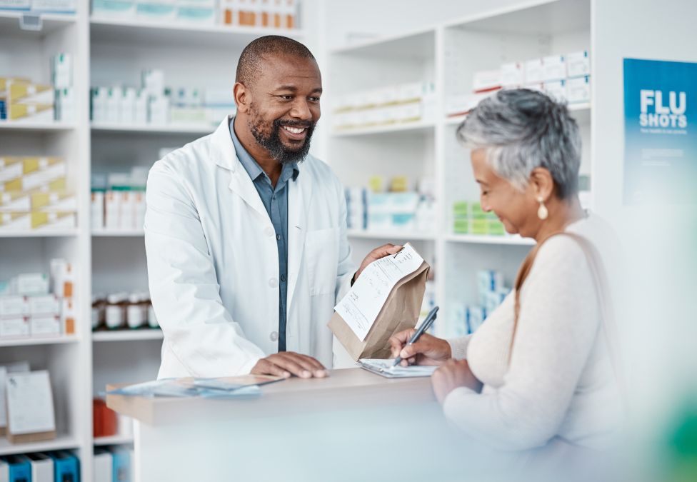 Pharmacist consulting with elderly female patient at pharmacy counter