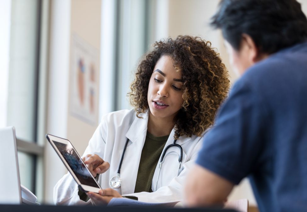 Healthcare worker consulting with patient at a desk with a tablet