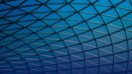 Geometric glass roof with triangular grid pattern in blue gradient light.
